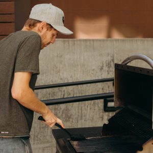 Man in hat cleaning the grill