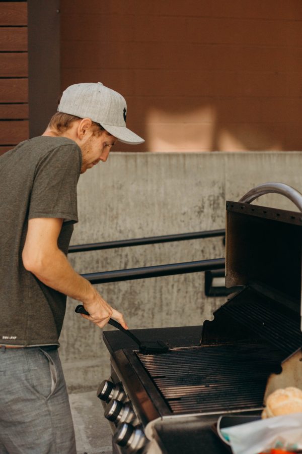 Man in hat cleaning the grill